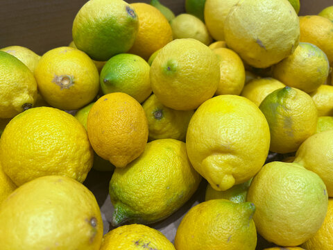 Fresh ripe lemons piled in a box displaying vibrant yellow citrus fruits