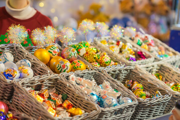 Handcrafted Christmas ornaments displayed in wicker baskets at festive holiday market. Concept of...