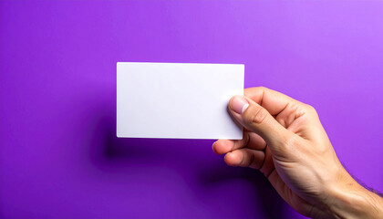 Fototapeta premium Hand holding blank card, vibrant purple background, minimalistic and clean presentation. Mock-up.