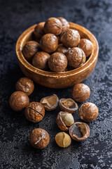 Tasty macadamia nuts in bowl on black table.