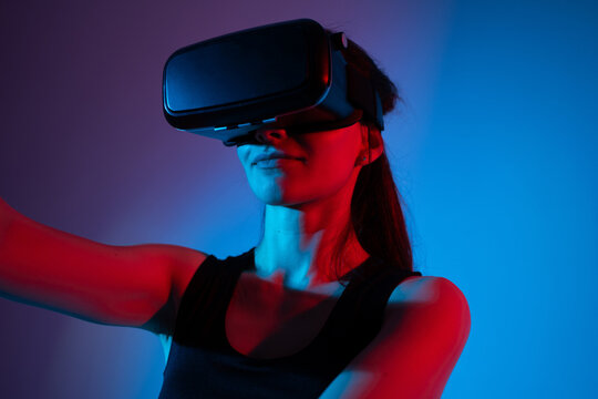 A female engineer researches VR technology in a neon environment, exploring virtual interfaces