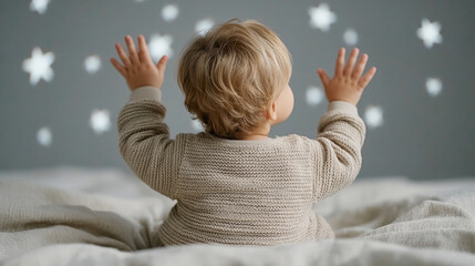 Caucasian toddler reaching for glowing stars on bedroom ceiling