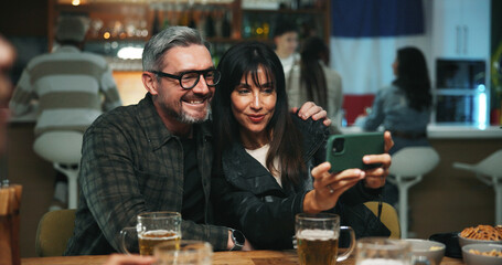 Selfie, love and couple in pub, happiness or bonding together with alcohol, relax or profile picture. People, men or mature woman with internet, relationship or celebration with memory or photography