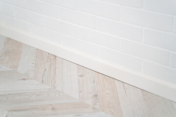 Modern interior with light wooden herringbone floor and white brick wall detail