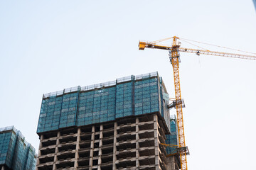 High rise construction site with yellow tower crane and unfinished concrete structure