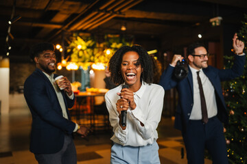 Diverse colleagues having fun singing karaoke at office party