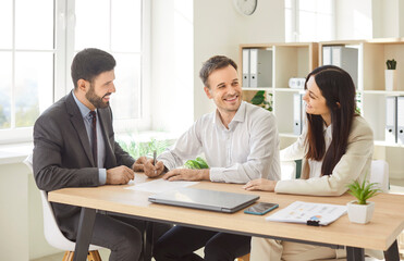 Couple of customers with a financial consultant or investment agent in an office, signing an important contract. Meeting highlights trust and professional guidance in managing financial decisions.