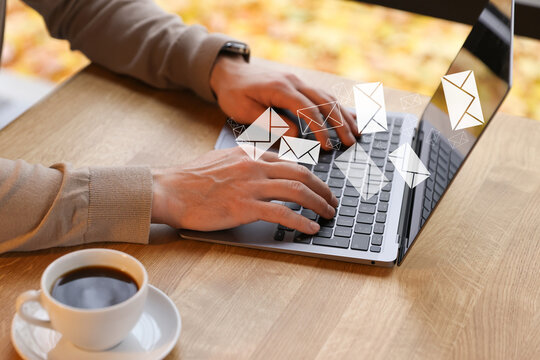 Man sending or receiving email on laptop at table, closeup. Letters flying out of screen - Powered by Adobe