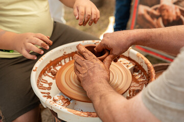 Child's Hands Learning Pottery on a Wheel with an Adult Instructor, Intergenerational Craft