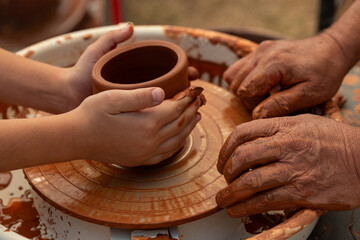 Child's Hands Learning Pottery on a Wheel with an Adult Instructor, Intergenerational Craft