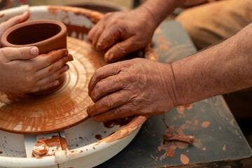 Child's Hands Learning Pottery on a Wheel with an Adult Instructor, Intergenerational Craft