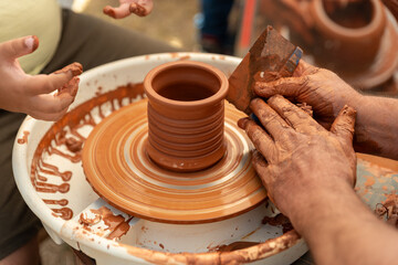 Child's Hands Learning Pottery on a Wheel with an Adult Instructor, Intergenerational Craft