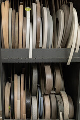 neatly stacked edgeband, textured paper sheets in a storage rack. Concept of organization, resourcefulness, and creative materials.