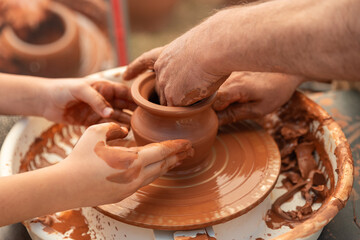 Child's Hands Learning Pottery on a Wheel with an Adult Instructor, Intergenerational Craft