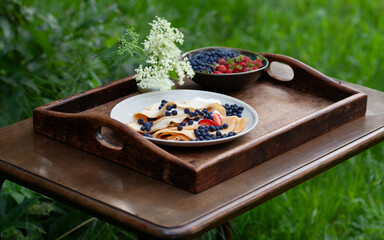 Delicious homemade crepes with fresh fruit  -  blueberry and alpine strawberry. Gourmet picnic snack ina spring garden.