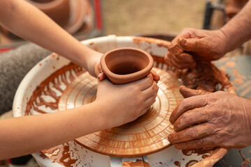 Child's Hands Learning Pottery on a Wheel with an Adult Instructor, Intergenerational Craft