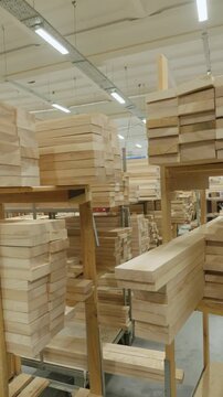 Stacked lumber fills a warehouse, neatly organized on shelving. Concept of resourcefulness, construction, or sustainable forestry is conveyed.