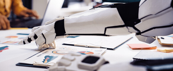 Robotic hand engaging with data charts in an office showcases the integration of technology into...