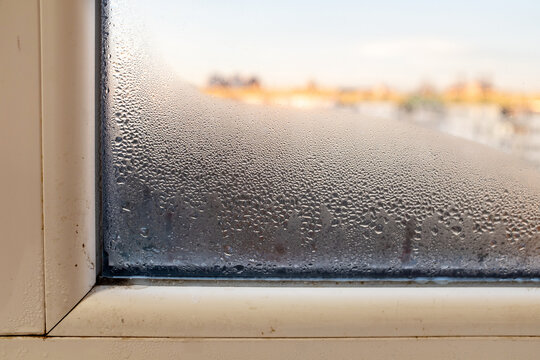 Condensation, mold, high humidity in the house. Foggy windows, humidity problem. high humidity in the house. hand wipes off water condensation from plastic window glass in the room 