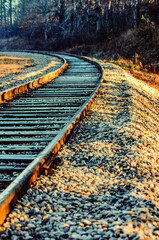 Empty curved railway tracks leading to the left during golden hour