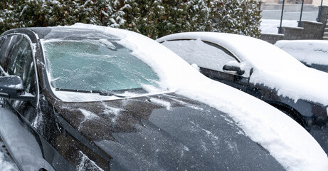 Cars covered with snow during winter snowfall in parking lot