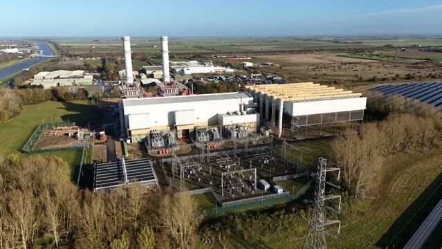 Aerial view of a large industrial complex with stark white buildings contrasting against the muted greens and browns of the surrounding landscape, Centenary Way, Spalding, England, United Kingdom.