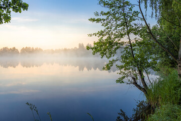 Morning landscape with fog and a pond. Dawn over the lake in the early morning.