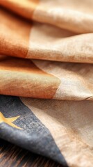 Close-up of folded fabric with abstract design in warm tones. The fabric has a textured appearance.