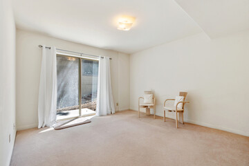 An empty living room with two chairs and a sliding glass door