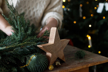 Making Christmas wreath. Hands arranging wreath with fir and cedar branches, and scissors, rustic...