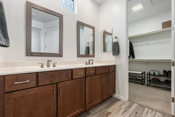 A spacious bathroom with two sinks, mirrors, and a large closet