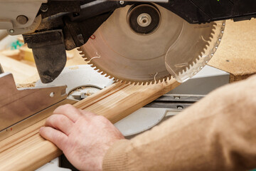 Close up of miter saw cutting wood trim in carpentry workshop