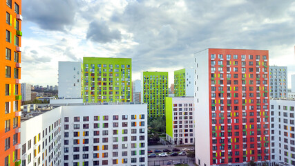 Colorful modern apartment buildings with bright facades and geometric windows under a cloudy sky. Concept of urban housing, modern architecture, and residential infrastructure in big cities