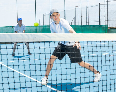 Young man is playing tennis on sunny day. Tennis serve match on hard court.