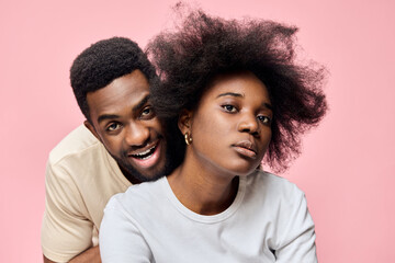 Obraz premium A joyful couple poses together in front of a pink background, showcasing natural hairstyles, vibrant emotions, and modern fashion choices, reflecting love and happiness