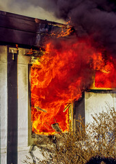 Intense fire coming through the window of a house fire.