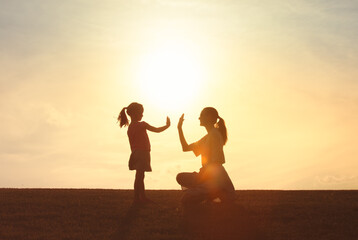 Mother and Daughter High Five at Sunset Silhouette