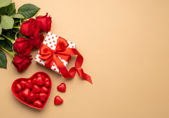 A flat lay image with a gift box, red roses, and heart-shaped candies on a beige background, perfect for romance and holidays.