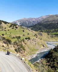 Scenic mountain landscape with river and motorcyclist on winding road