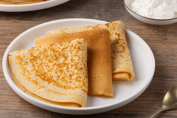 Traditional Russian pancakes with sour cream on a wooden table. Homemade russian thin pancakes blini. Russian food, russian kitchen