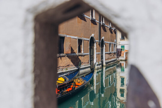 Venice canal with gondolas seen through archway - Powered by Adobe