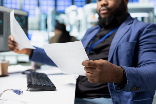 African american male consultant for energy in a factory setting reviews data, managing efficiency and innovation within solar panel manufacturing. Engineering precision and sustainability. - Powered by Adobe