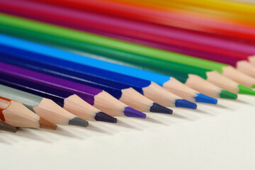 New wooden colored pencils of rainbow colors, perfectly sharpened, lie on table
