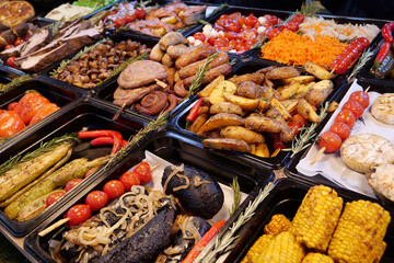 Meat, sausages, fried potatoes, champignon mushrooms, corn, tomatoes, vegetables