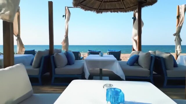 Elegant beachside lounge with white tables and blue sofas faces the ocean.