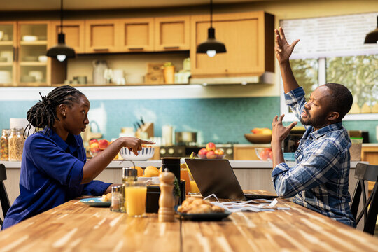 Mad displeased partners screaming and blaming each other for debts, feeling worried and stressed about money problems and irresponsibility. Angry man and woman in conflict at home.