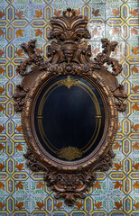 Antique baroque frame on a wall of vintage ceramic glazed wall tiles or azulejos 
