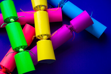 Brightly colored Christmas crackers piled onto a background of purple copy space