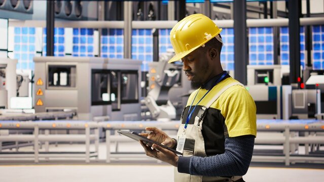 Technician in industrial plant using tablet app to diagnose equipment errors. Manufacturing factory specialist using digital device to coordinate repair tasks on assembly lines, camera A