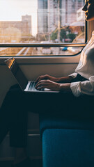 Woman working remotely on a train at sunset. Concept for modern lifestyle, productivity, commuting. Evokes flexibility and worklife balance.
